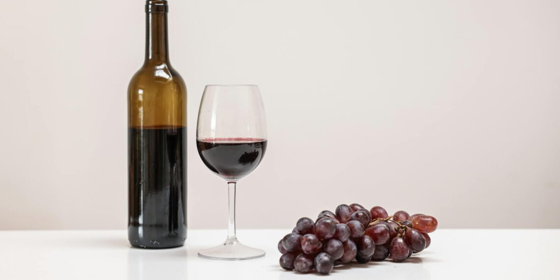a bottle of wine near the wine glass and grapes on the table